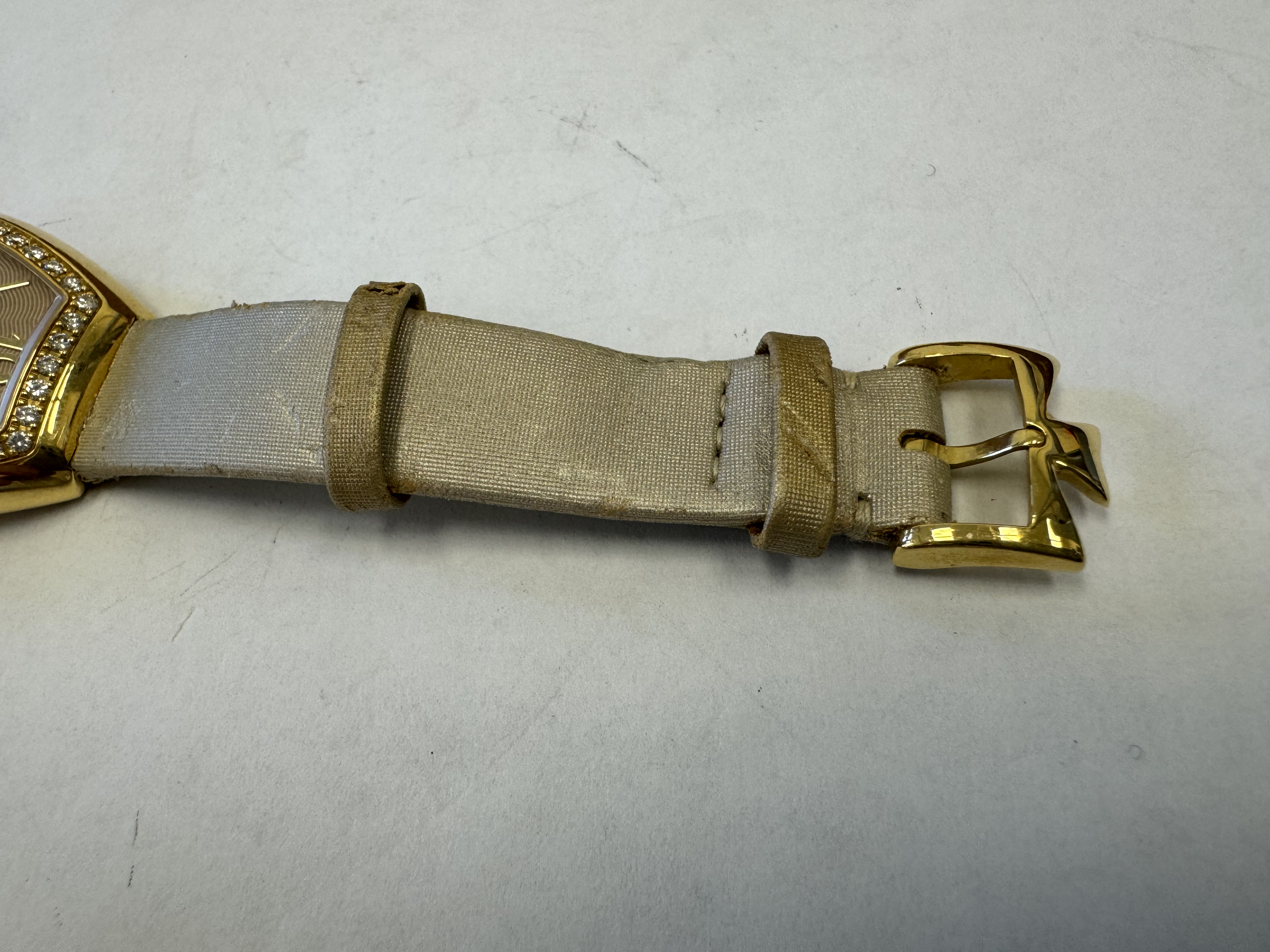 Наручные часы «Vacheron Constantin Egerie ref. 25540», корпус овальный из металла золотистого цвета со вставкой из прозрачных камней по кругу. Ремешок из материала светлого цвета с замком из металла золотистого цвета, на оборотной стороне штампованная надпись «VACHERON CONSTANTIN», «GENEVE», «777369», «25540», б/у.