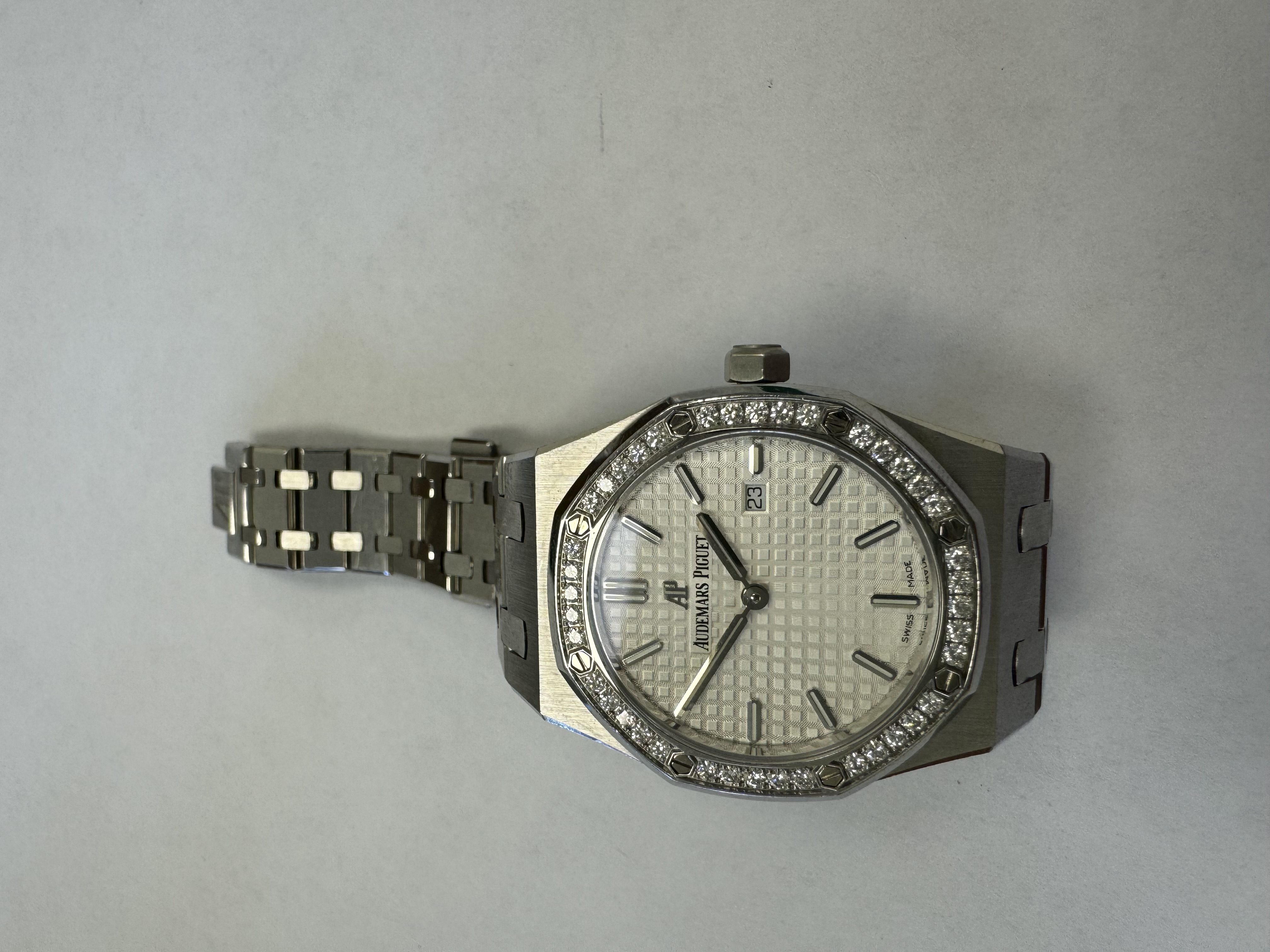 Наручные часы «Audemars Piguet Royal Оаk Quartz 33 Ladies ref. 67651st.zz.1261st.01»корпус из металла серебристого цвета ромбовидной формы со вставками из прозрачных камней по кругу. На оборотной стороне штампованная надпись «ROYAL QAK», «№ 6657», «I 84034», б/у