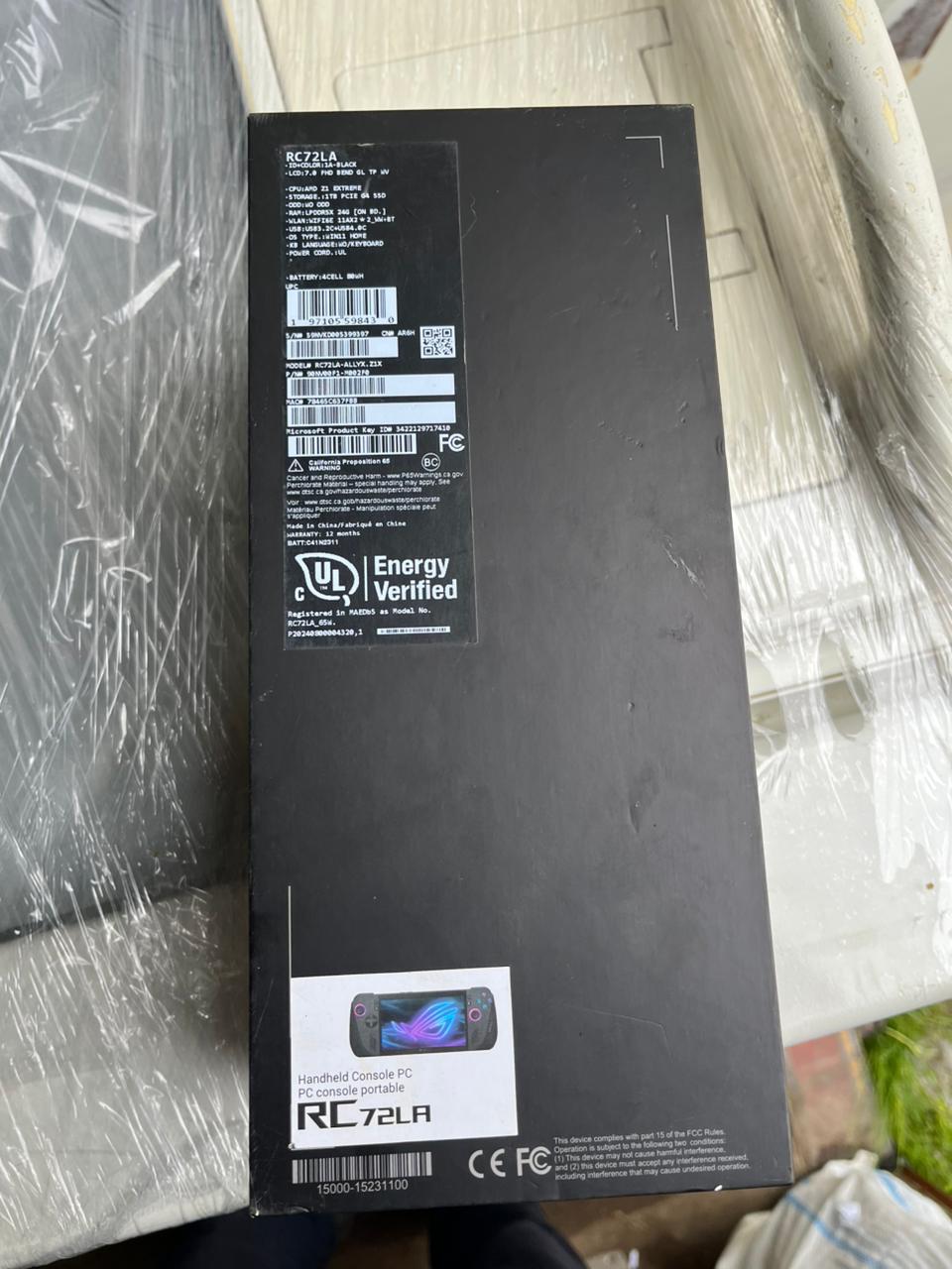 Картонная коробка черного цвета с рисунками и надписью ROG ALLY X, внутри коробки находится игровая консоль черного цвета