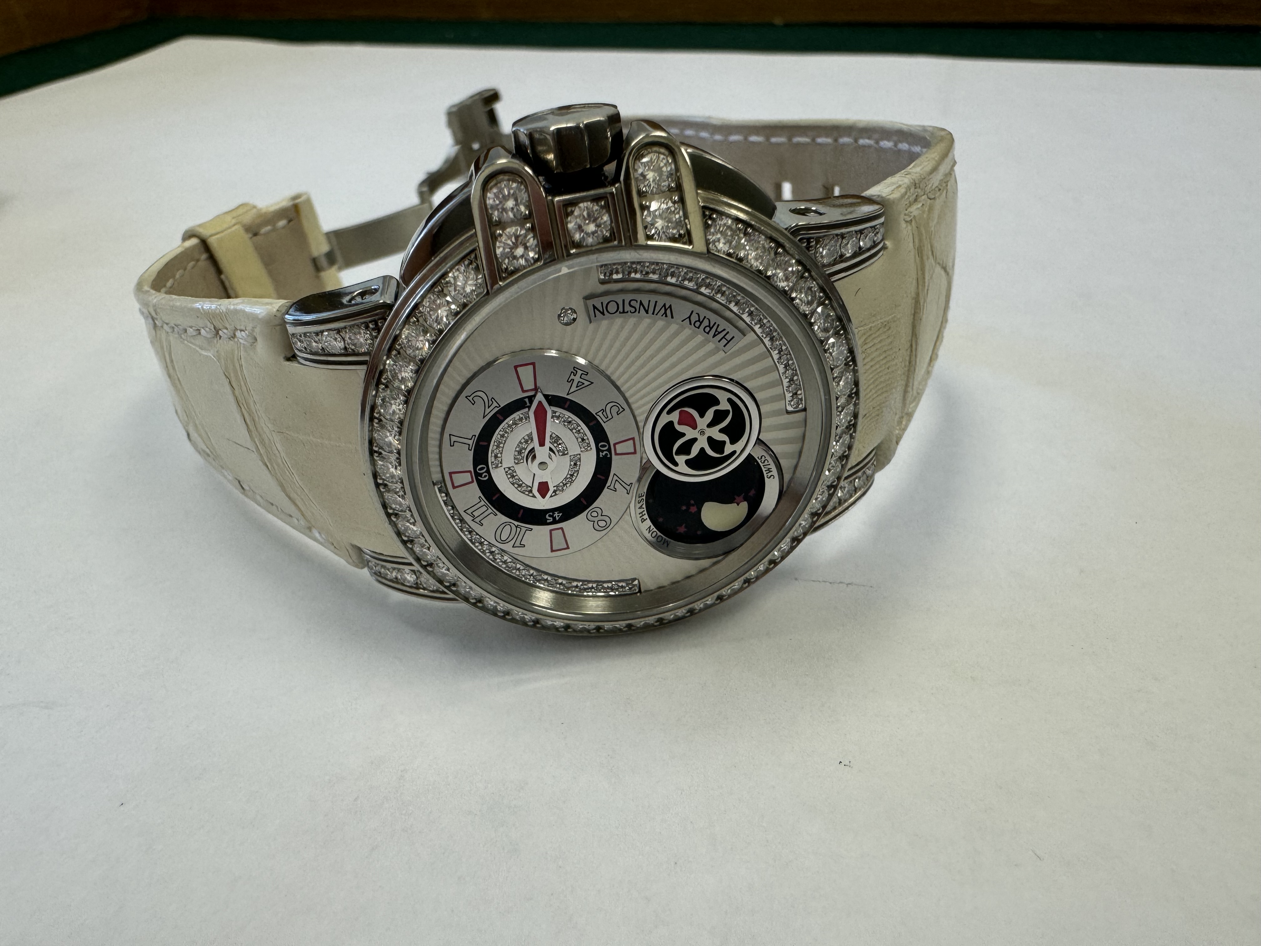 Наручные часы «Наrrу Winston Осеаn Lady Z Moonphase 400/UAMP36ZL.WDR/D3.1» Корпус круглый из металла серебристого цвета со вставками из прозрачных камней по кругу. Ремешок из металла белого цвета с замком из металла серебристого цвета, на оборотной стороне штампованная надпись «HARRY WINSTON», «Zalium № 08/50», «SWISS MADE 045967», «400 UAMP36Z», б/у.