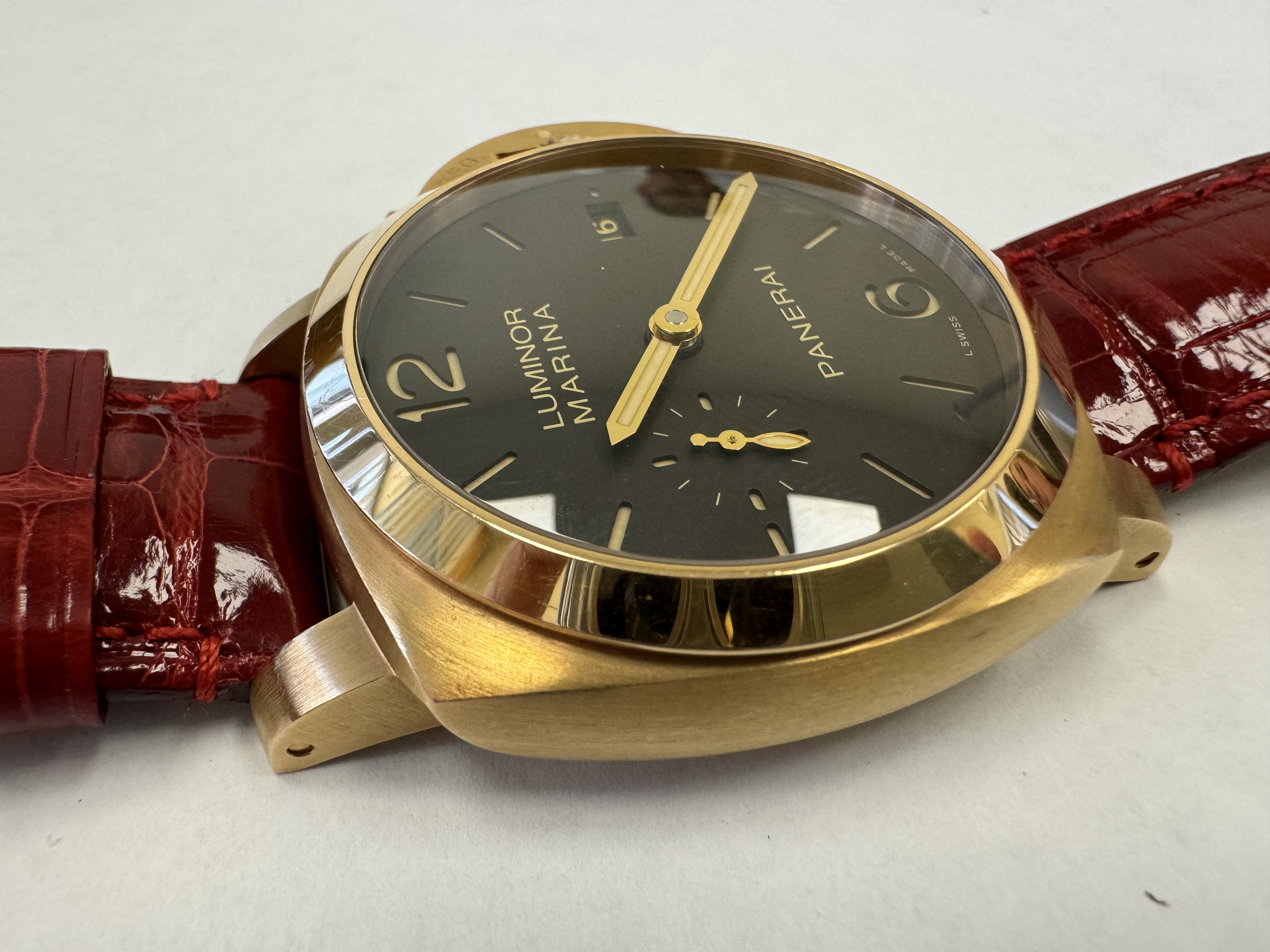 Наручные часы «Panerai Luminor Marina 1950 З Days ref. РАМ00З9З»»,корпус круглый, из металла золотистого цвета, ремешок из материала красного цвета с замком из металла золотистого цвета. На оборотной стороне штампованная надпись «OFFICINE PANERA», «0 130/500», «BB1538538», «OP 6889», «Au750», «50m», б/у