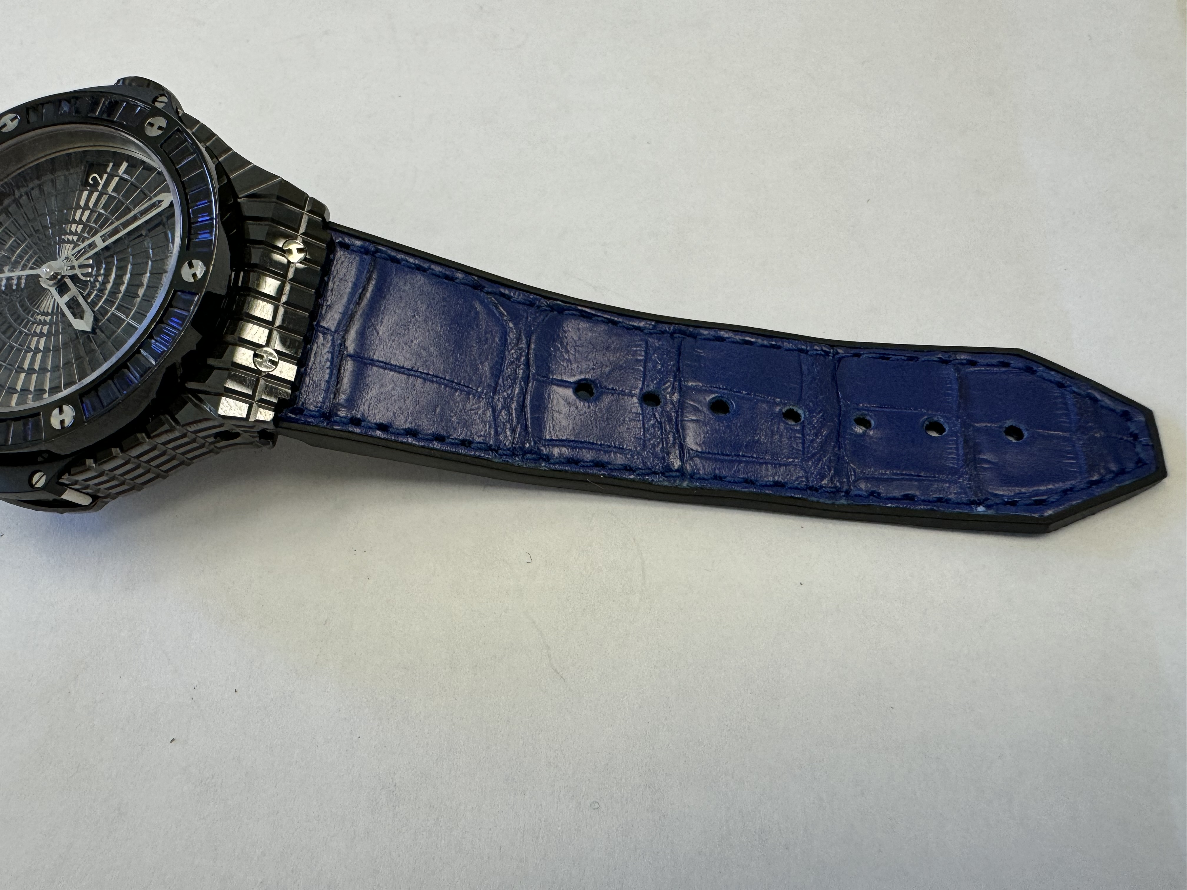 Наручные часы «Hublot Big Bang Tutti Fruitti Dark Blue Caviar ref. 346.CD.1800.LR.1901»в круглом корпусе из металла темного цвета со вставками синего цвета. Часы имеют ремешок из материала синего цвета с замком из металла черного цвета. На оборотной стороне часов имеется надпись «HUBLOT», «BIG BANG», «946159», б/у