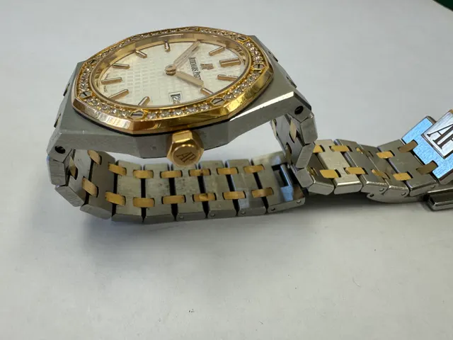 Наручные часы «Audemars Piguet Royal Оаk Quartz Ladies 67651SR.ZZ.1261SR.01», корпус ромбовидный, из металла серебристого цвета со вставкой золотистого цвета; по кругу — вставка из прозрачных камней. Браслет из металла серебристого цвета со вставками золотистого цвета с замком. На оборотной стороне штампованная надпись «ROYAL OAK», «№ 0464», «J 01230», б/у