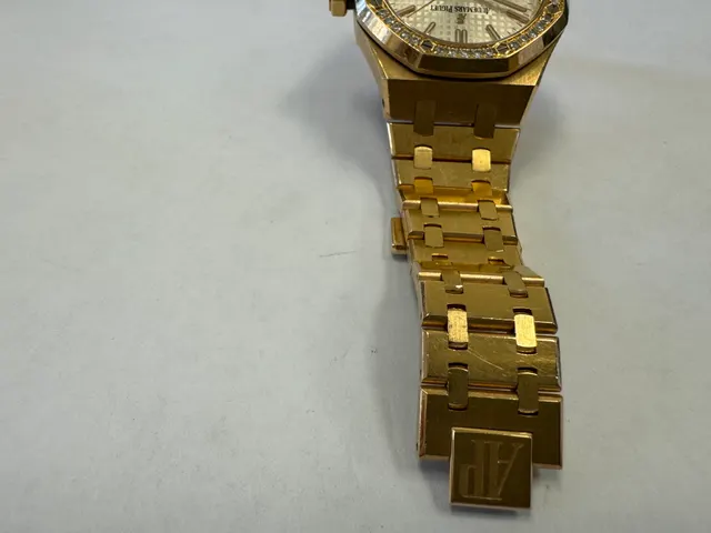 Наручные часы «Audemars Piguet Royal Оаk Auto 37 Ladies ref. 15451or.zz.1256or.01»корпус ромбовидный, из металла золотистого цвета со вставкой из прозрачных камней по кругу, браслет из металла золотистого цвета с замком. На оборотной стороне штампованная надпись «ROYAL OAK», «№ 1163», «I 24742», «Au750», б/у.