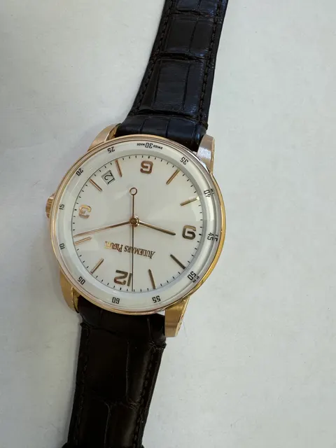 Наручные часы «Audemars Piguet CODE 11.59Automatic ref. 15210OR.OO.A099CR.01»корпус круглый, из металла золотистого цвета, ремешок из материала коричневого цвета с замком из маталла золотистого цвета. На оборотной стороне штампованная надпись "AUDEMARS PIGUET", "K34245", "Au750", б/у.