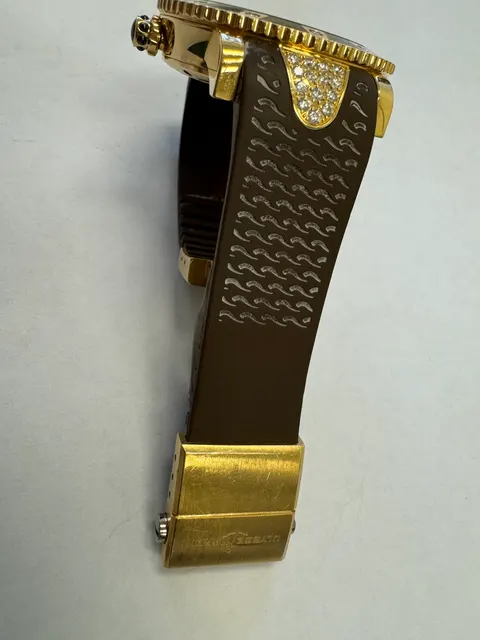 Наручные часы «Ulysse Nardin Marine Diver ref. 8106-101» в круглом корпусе из металла золотистого цвета с вставками в виде прозрачных камней по кругу. Часы имеют ремешок из материала коричневого цвета с замком из металла серебристого и золотистого цветов. На оборотной стороне часов имеется штампованная надпись «ULYSSE NARDIN», «100 METERS», «№1826», б/у.