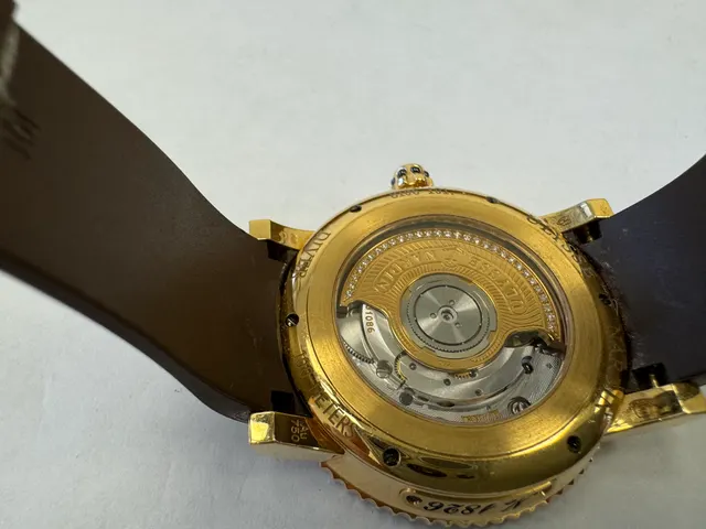 Наручные часы «Ulysse Nardin Marine Diver ref. 8106-101» в круглом корпусе из металла золотистого цвета с вставками в виде прозрачных камней по кругу. Часы имеют ремешок из материала коричневого цвета с замком из металла серебристого и золотистого цветов. На оборотной стороне часов имеется штампованная надпись «ULYSSE NARDIN», «100 METERS», «№1826», б/у.